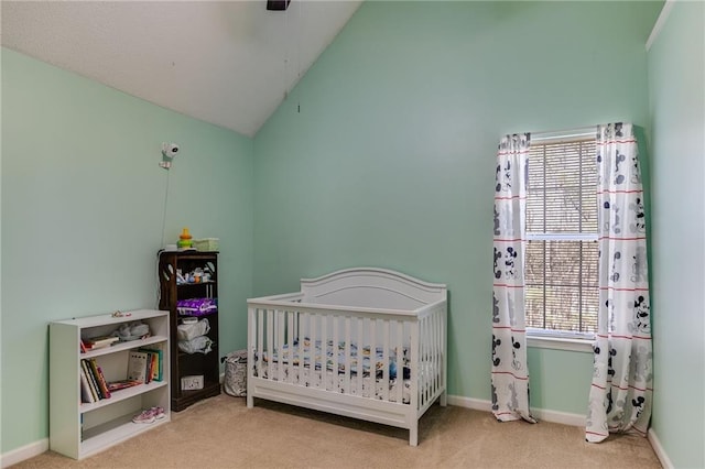 bedroom with carpet flooring, vaulted ceiling, a crib, and baseboards