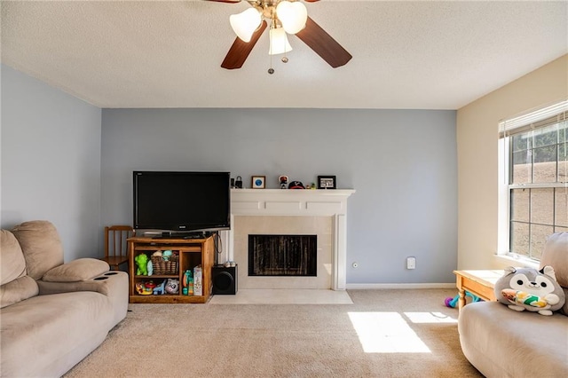 living area featuring a fireplace with flush hearth, carpet flooring, ceiling fan, and a textured ceiling