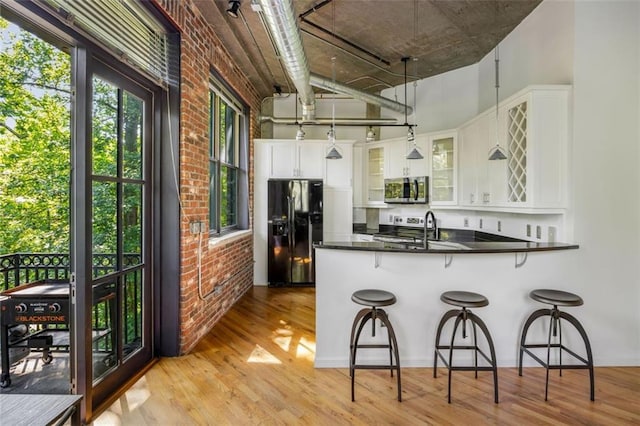 3235 Roswell Rd NE Unit 505, Atlanta, GA 30305 - kitchen with stainless steel appliances, brick wall, light wood-style flooring, dark countertops, and glass insert cabinets