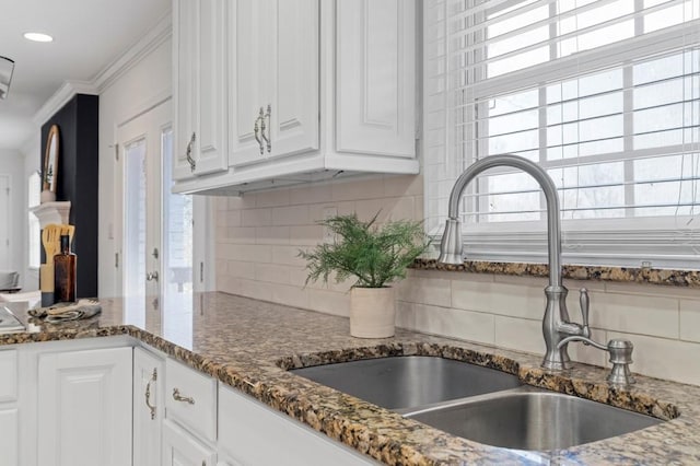 kitchen with white cabinetry, a healthy amount of sunlight, dark stone counters, and sink