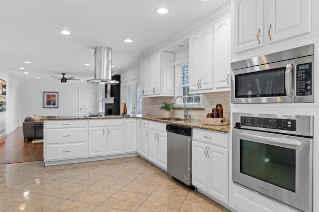 kitchen featuring appliances with stainless steel finishes, white cabinetry, sink, light stone counters, and kitchen peninsula