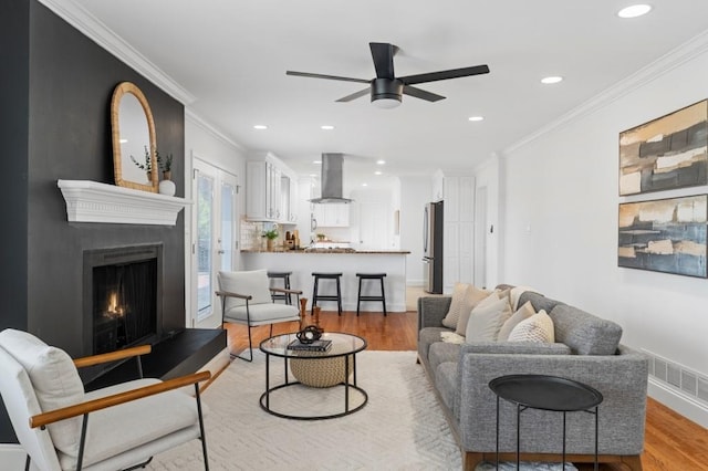 living room with crown molding, light hardwood / wood-style floors, and ceiling fan