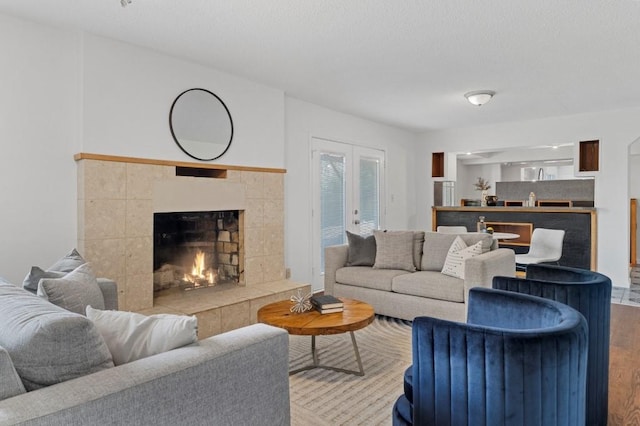 living room featuring french doors, a tile fireplace, and light hardwood / wood-style flooring