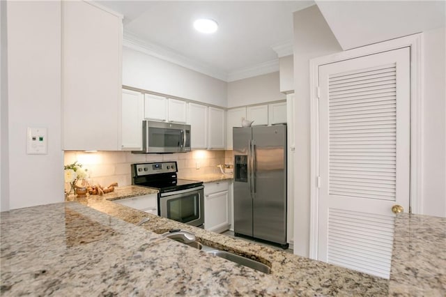 kitchen with light stone countertops, white cabinetry, stainless steel appliances, crown molding, and decorative backsplash