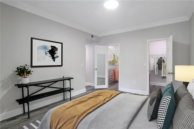 bedroom with ensuite bath, a spacious closet, ornamental molding, and a closet