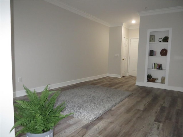 unfurnished room with built in shelves, crown molding, and dark wood-type flooring