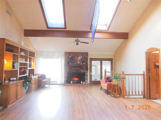 living room with beamed ceiling, a skylight, and hardwood / wood-style floors