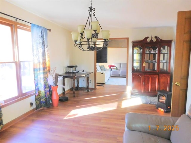 dining area featuring a notable chandelier, light hardwood / wood-style floors, and a wood stove