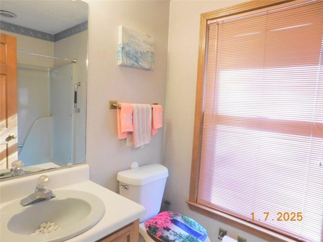 bathroom with walk in shower, vanity, and toilet