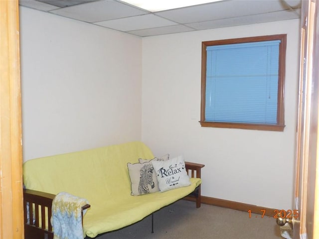 living area with a paneled ceiling and carpet