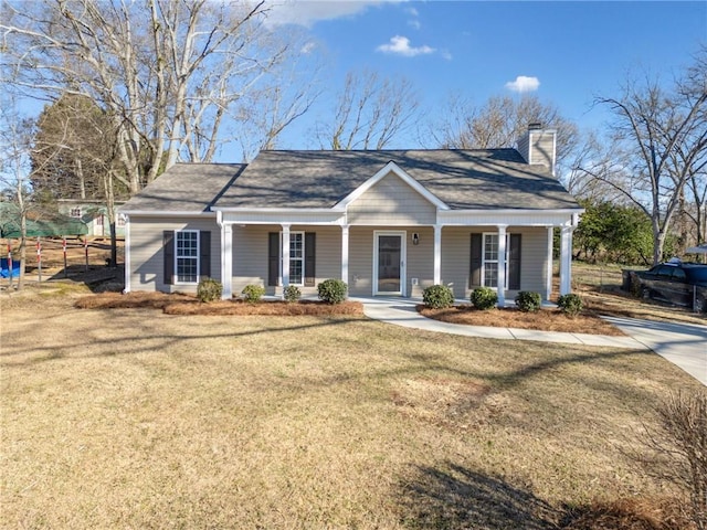 view of front facade with a porch, a front yard, fence, and a chimney