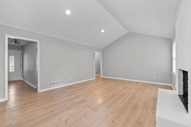 unfurnished living room with light wood-type flooring, vaulted ceiling, and a fireplace