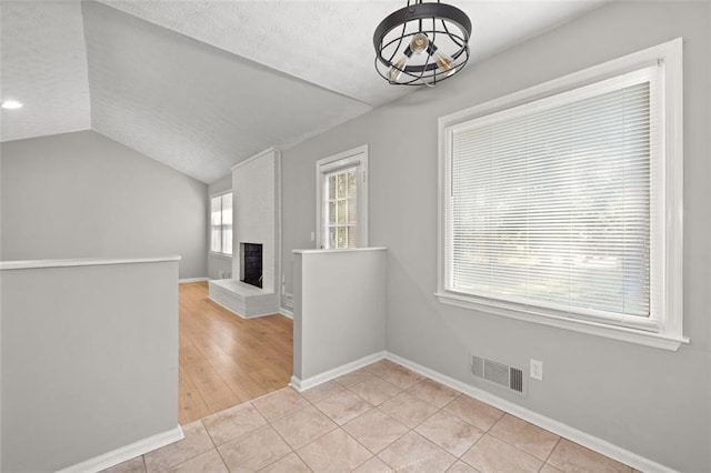 interior space with a fireplace, lofted ceiling, and light tile patterned flooring