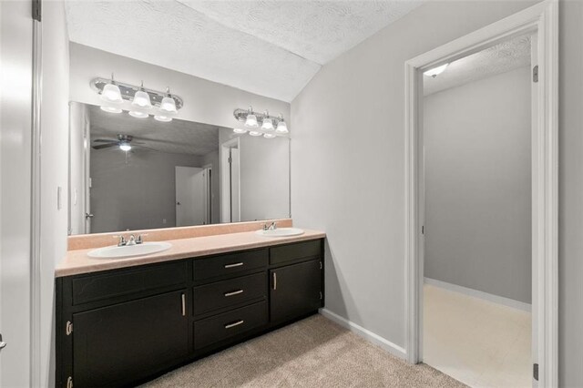 bathroom featuring ceiling fan, double sink vanity, a textured ceiling, and lofted ceiling