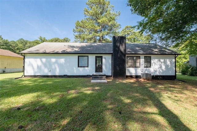 back of house with central AC unit and a yard