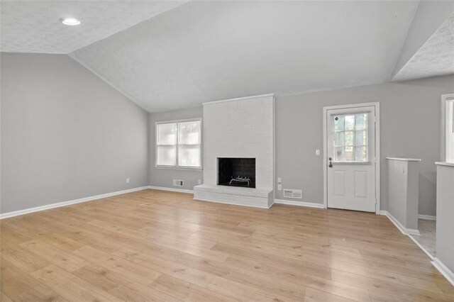 unfurnished living room featuring a fireplace, light hardwood / wood-style floors, and lofted ceiling