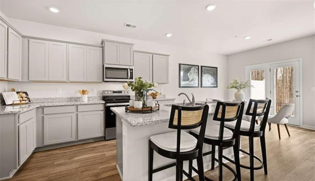 321 Sound Cir, Stockbridge, GA 30281 - kitchen featuring stainless steel appliances, gray cabinets, a kitchen island with sink, wood finished floors, and recessed lighting