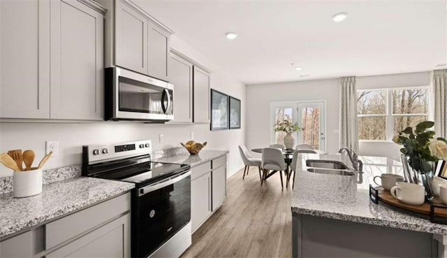 321 Sound Cir, Stockbridge, GA 30281 - kitchen with stainless steel appliances, light wood-style floors, light stone counters, gray cabinetry, and recessed lighting