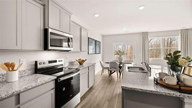 321 Sound Cir, Stockbridge, GA 30281 - kitchen with appliances with stainless steel finishes, light stone counters, light wood-type flooring, gray cabinetry, and recessed lighting