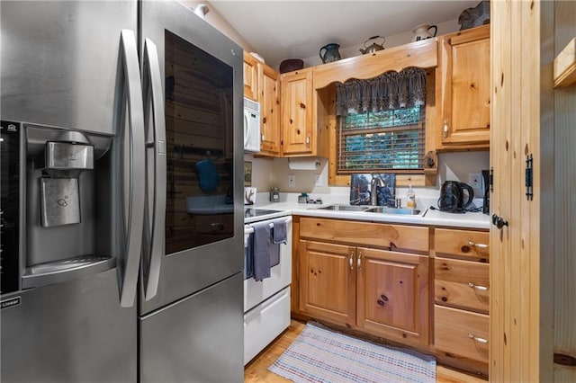 kitchen with a sink, white appliances, light wood-style floors, and light countertops