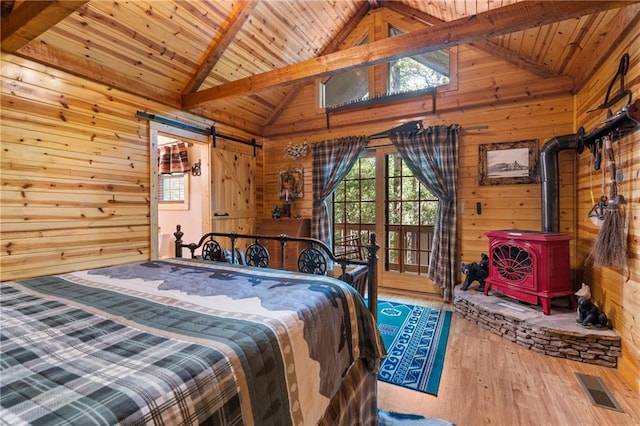 bedroom with wood finished floors, visible vents, wood ceiling, wood walls, and a barn door