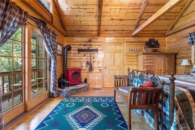 bedroom featuring wood finished floors, wooden walls, wooden ceiling, vaulted ceiling with beams, and a wood stove