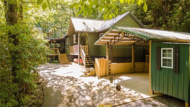 view of side of property featuring a carport, stairway, and metal roof