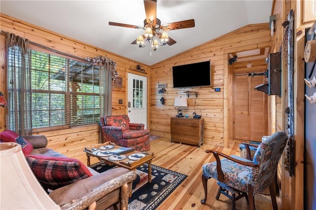 living room with plenty of natural light, wooden walls, hardwood / wood-style flooring, and vaulted ceiling