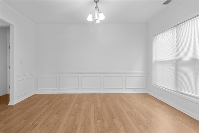 empty room with light hardwood / wood-style flooring, an inviting chandelier, and ornamental molding