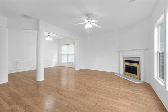 unfurnished living room featuring a fireplace, light hardwood / wood-style floors, and ceiling fan with notable chandelier