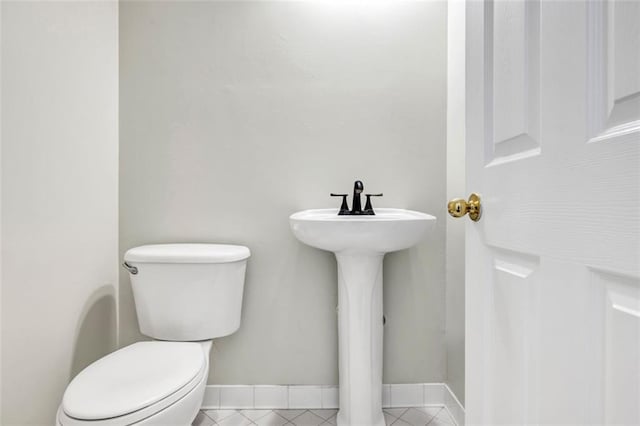 bathroom with toilet, tile patterned floors, and sink