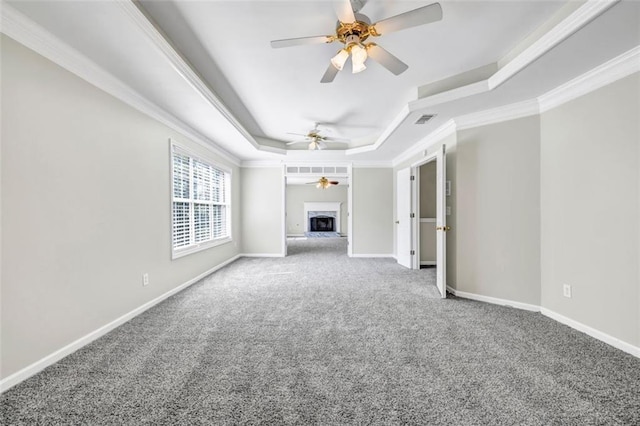 unfurnished living room with crown molding, carpet flooring, and a raised ceiling