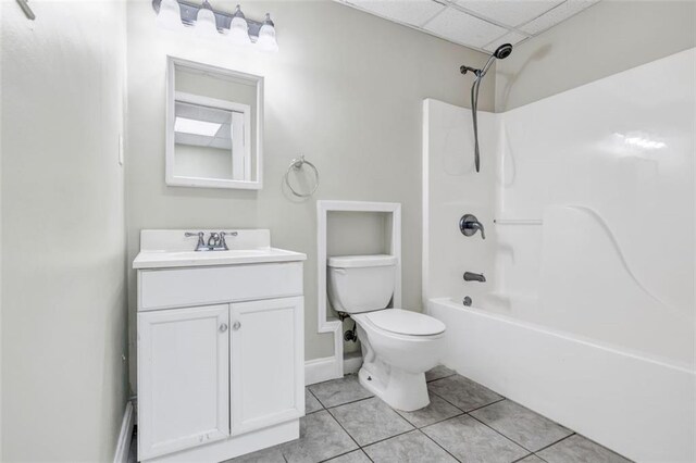 full bathroom featuring tile patterned floors, toilet, vanity, washtub / shower combination, and a paneled ceiling