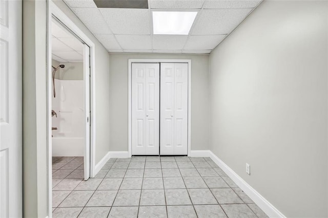 unfurnished bedroom with a closet, a paneled ceiling, and light tile patterned flooring