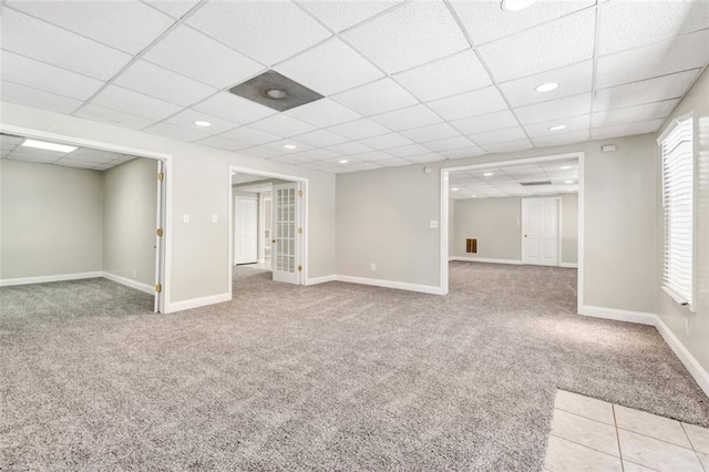 basement featuring a drop ceiling and light colored carpet