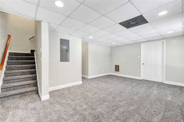 basement featuring a paneled ceiling, carpet flooring, and electric panel