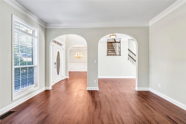 empty room featuring ornamental molding, a notable chandelier, and dark hardwood / wood-style flooring