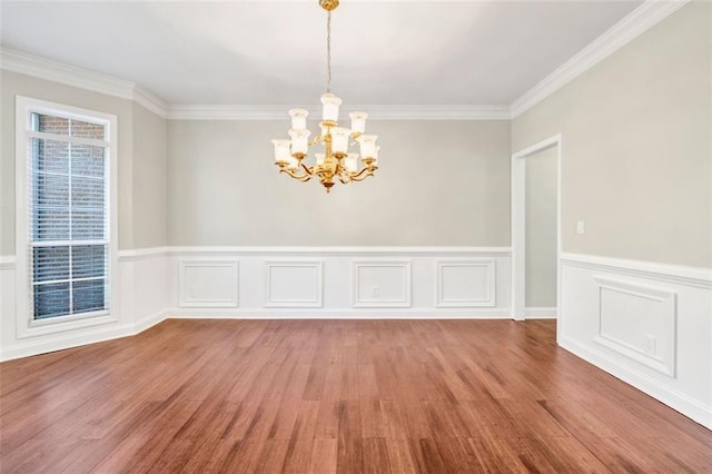 spare room featuring an inviting chandelier, crown molding, and wood-type flooring