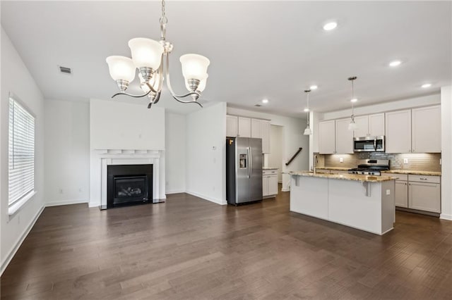 1637 Short Shadow Ln, Snellville, GA 30078 - kitchen featuring appliances with stainless steel finishes, open floor plan, backsplash, a chandelier, and light stone counters