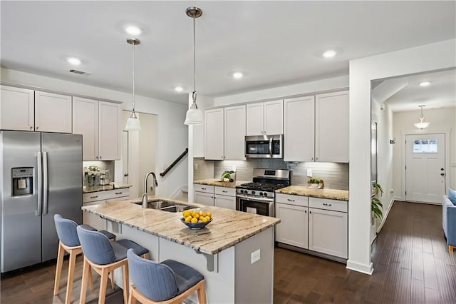 1637 Short Shadow Ln, Snellville, GA 30078 - kitchen with appliances with stainless steel finishes, decorative backsplash, a breakfast bar area, an island with sink, and pendant lighting
