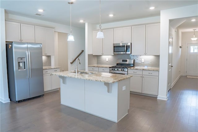 1637 Short Shadow Ln, Snellville, GA 30078 - kitchen with stainless steel appliances, decorative backsplash, an island with sink, white cabinetry, and dark wood-style flooring