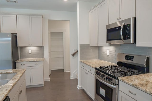 1637 Short Shadow Ln, Snellville, GA 30078 - kitchen featuring appliances with stainless steel finishes, white cabinetry, tasteful backsplash, and light stone counters