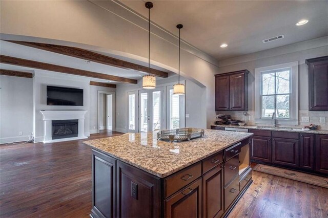 kitchen featuring light stone counters, a center island, and dark brown cabinets