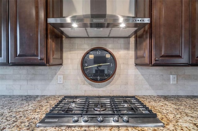 kitchen with light stone countertops, dark brown cabinets, and wall chimney exhaust hood