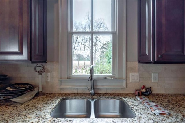 kitchen featuring sink, backsplash, and light stone countertops