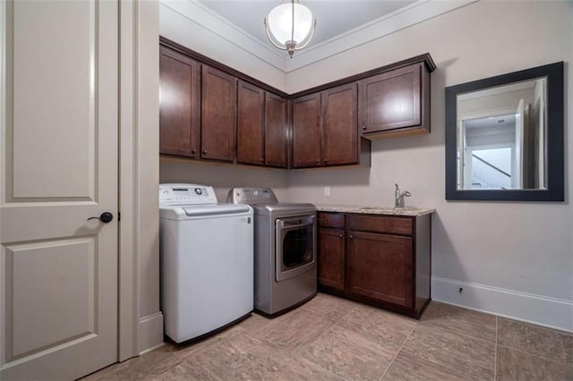 clothes washing area featuring cabinets, sink, and washer and dryer