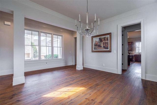 unfurnished dining area featuring dark wood-type flooring, ornate columns, ornamental molding, and a notable chandelier