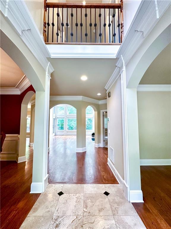 entrance foyer featuring hardwood / wood-style flooring, ornamental molding, and a high ceiling