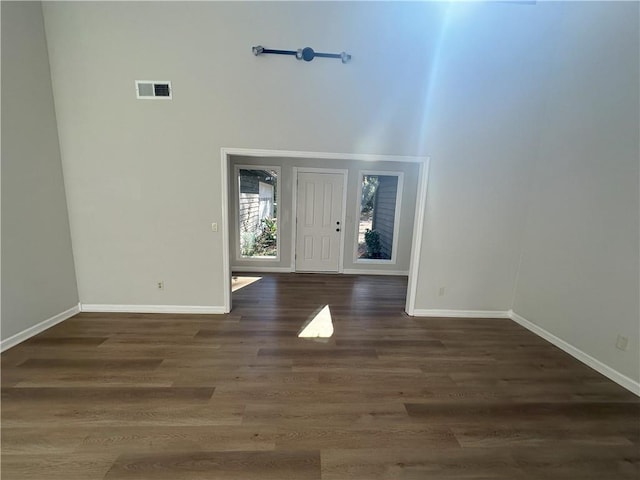 foyer entrance with visible vents, dark wood-type flooring, baseboards, and a towering ceiling