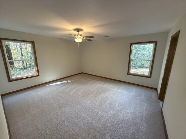 empty room with a healthy amount of sunlight, light colored carpet, and baseboards